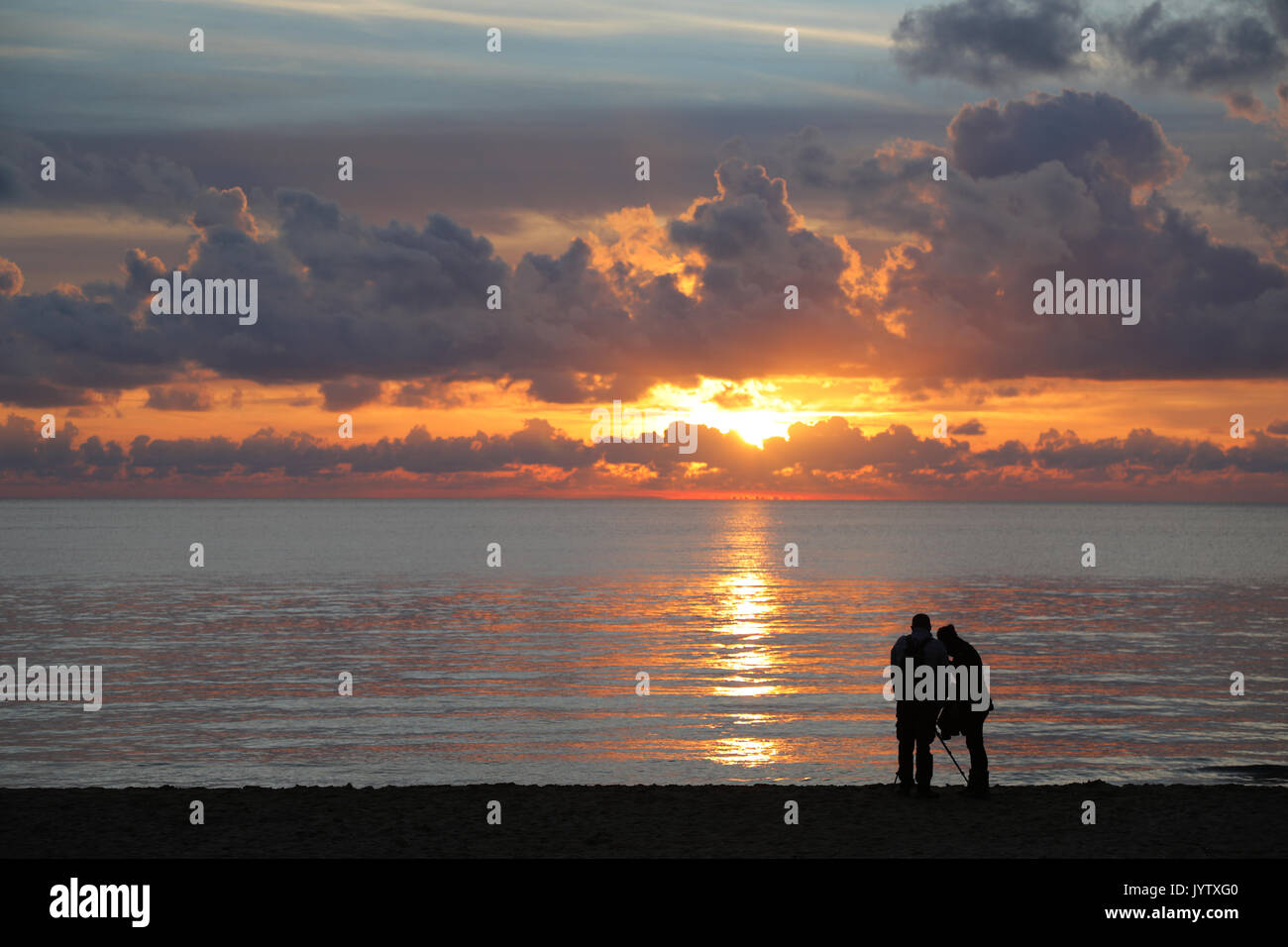 Silhouetten der beiden nicht identifizierbare Personen am Strand Fotos von Sonnenuntergang über dem Meer Stockfoto