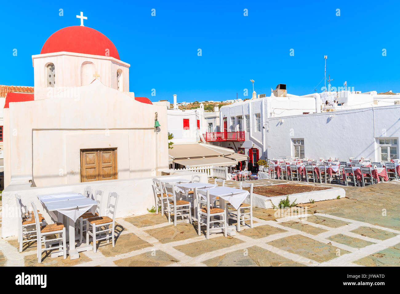 Typische Griechische weiße Kirche und Taverne Tabellen in der Stadt Mykonos, Insel, Griechenland Stockfoto