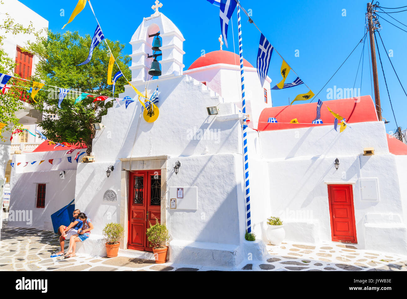 Insel Mykonos, Griechenland - 17. MAI 2016: Paar junge Touristen, die sich auf kleinen Platz mit Kirche Auf weiß getünchten Straße im wunderschönen Mykonos Stockfoto