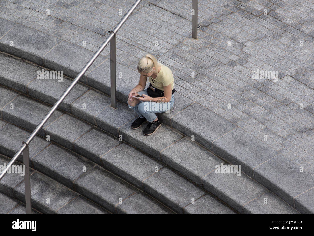 Junges Mädchen sitzt auf die Schritte der Suche können Sie über Ihr Mobiltelefon. Stockfoto