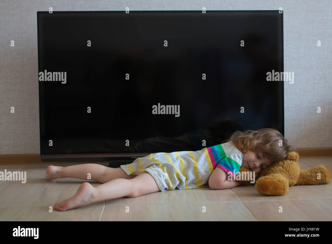 Konzeptionelle portrait Mädchen ist auf dem Boden zu schlafen auf dem Hintergrund einer schwarz TV-Bildschirm Stockfoto