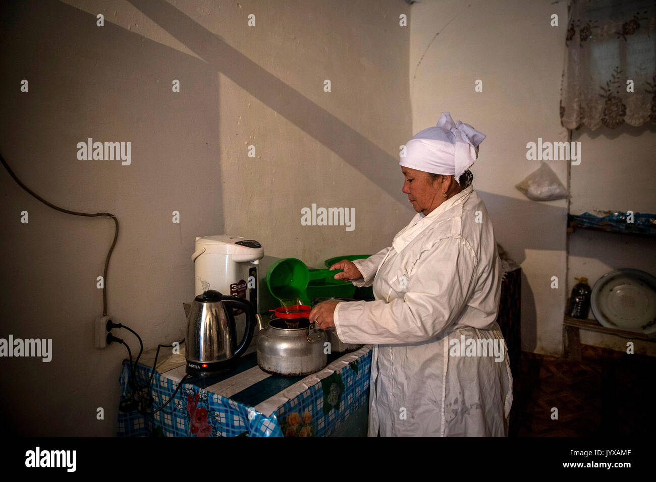 Anabar Nosirova, die in der Küche der Beshkent Schule arbeitet. Sie sammelt täglich 80-100 Liter Wasser aus einem nahe gelegenen aryk, die Sie filtern das Wasser durch Käse Tuch und lässt sie über Nacht so sitzen der Staub legt sich auf den Boden. Am nächsten Morgen war sie kocht das Wasser, bevor der Kaffee für die Studierenden. Die Einheimischen sind Hoffnung und Planung für die Infrastruktur Projekt sauberes Wasser in ihre Häuser, Schulen und medizinischen Einrichtungen zu bringen. In den Dörfern über Kirgisistan (Zentralasien) antiquierte Wasserversorgung und Infrastruktur ist die Ursache für gesundheitliche Aspekte wie Ausbrüche von Stockfoto