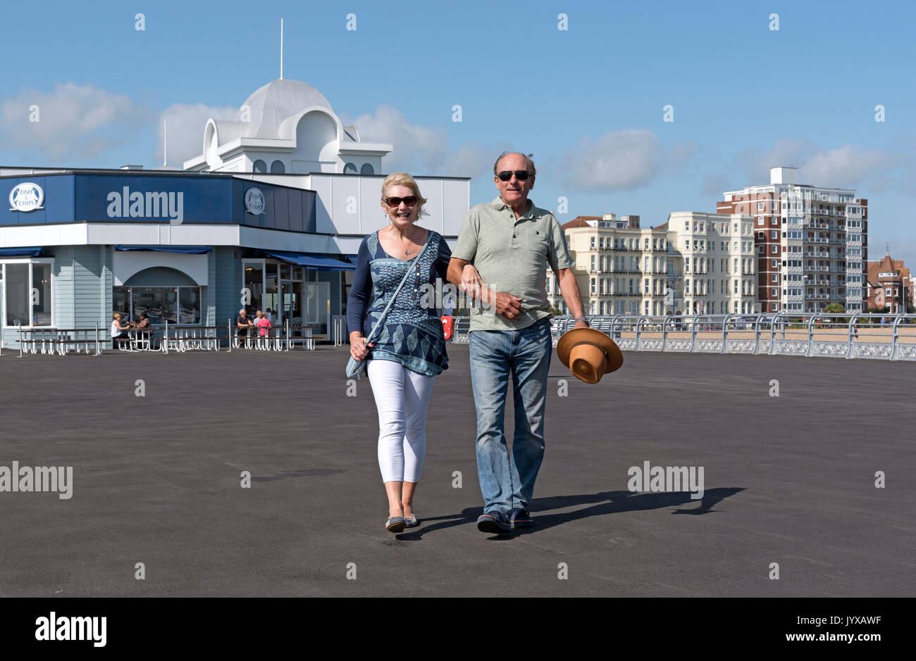 Ältere paar Urlauber gehen Arm in Arm auf einem Pier am Meer im Süden von England Großbritannien Stockfoto