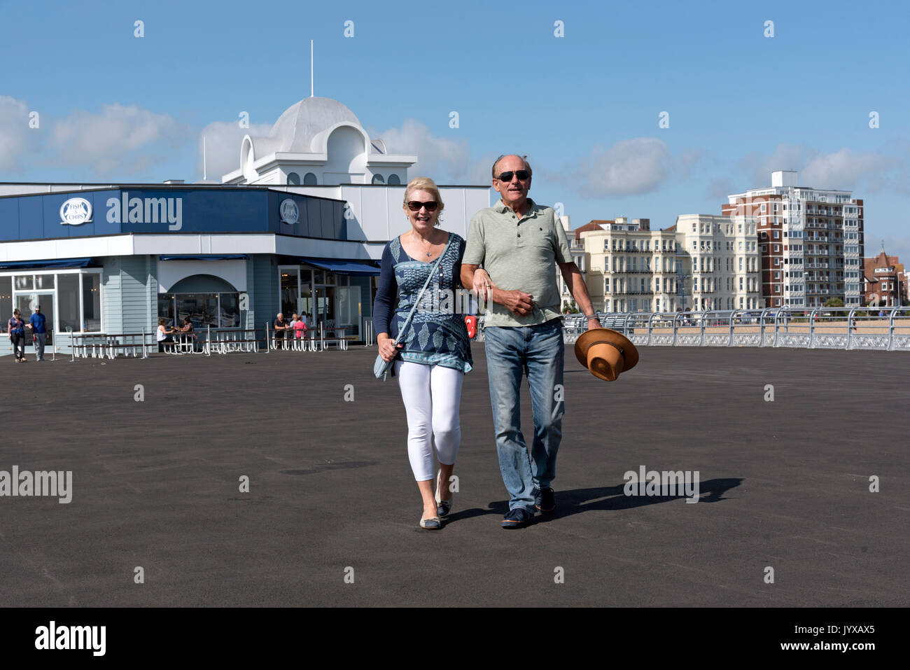 Ältere paar Urlauber gehen Arm in Arm auf einem Pier am Meer im Süden von England Großbritannien Stockfoto