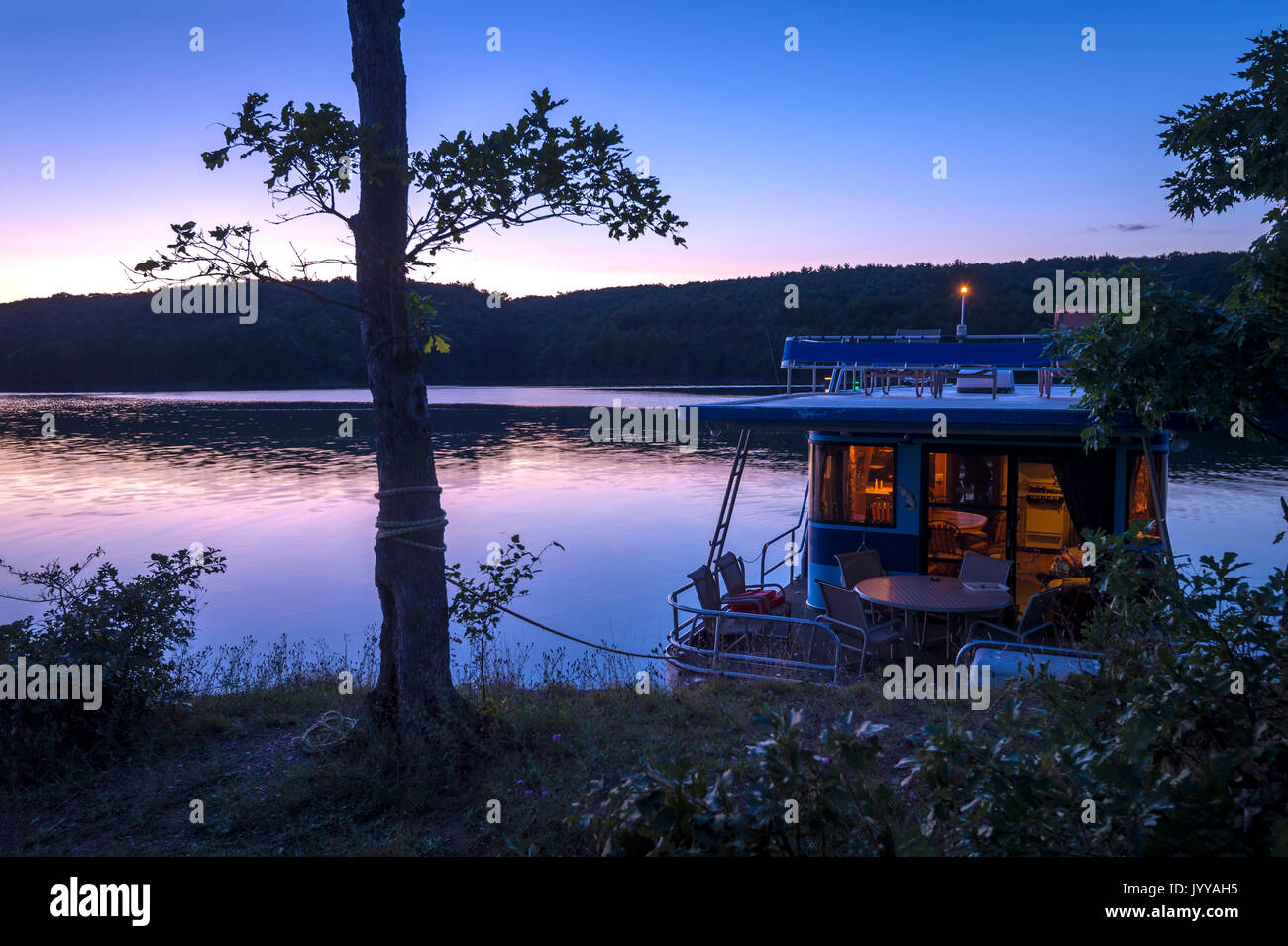 Hausboot gebunden bis zum Ufer bei Sonnenuntergang Stockfoto