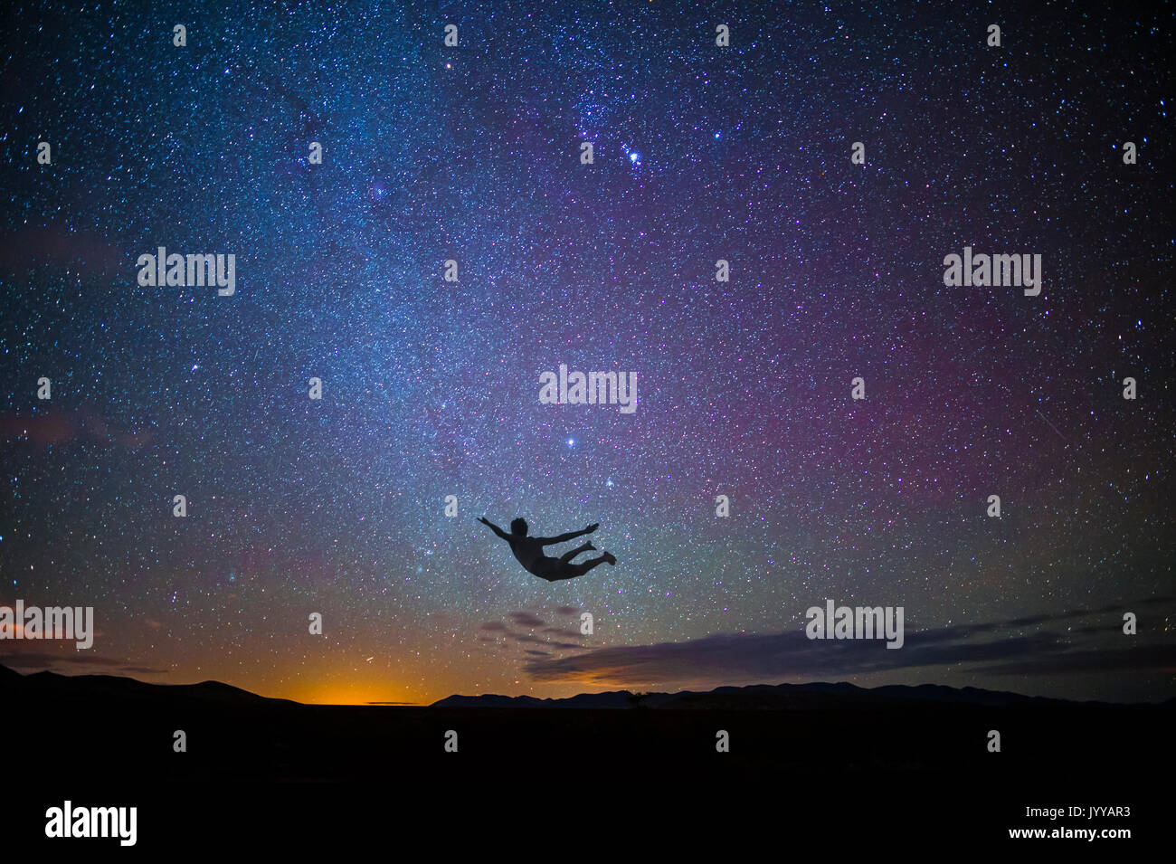Boy Jumping in Luft bei Sonnenuntergang mit Sternen Stockfoto