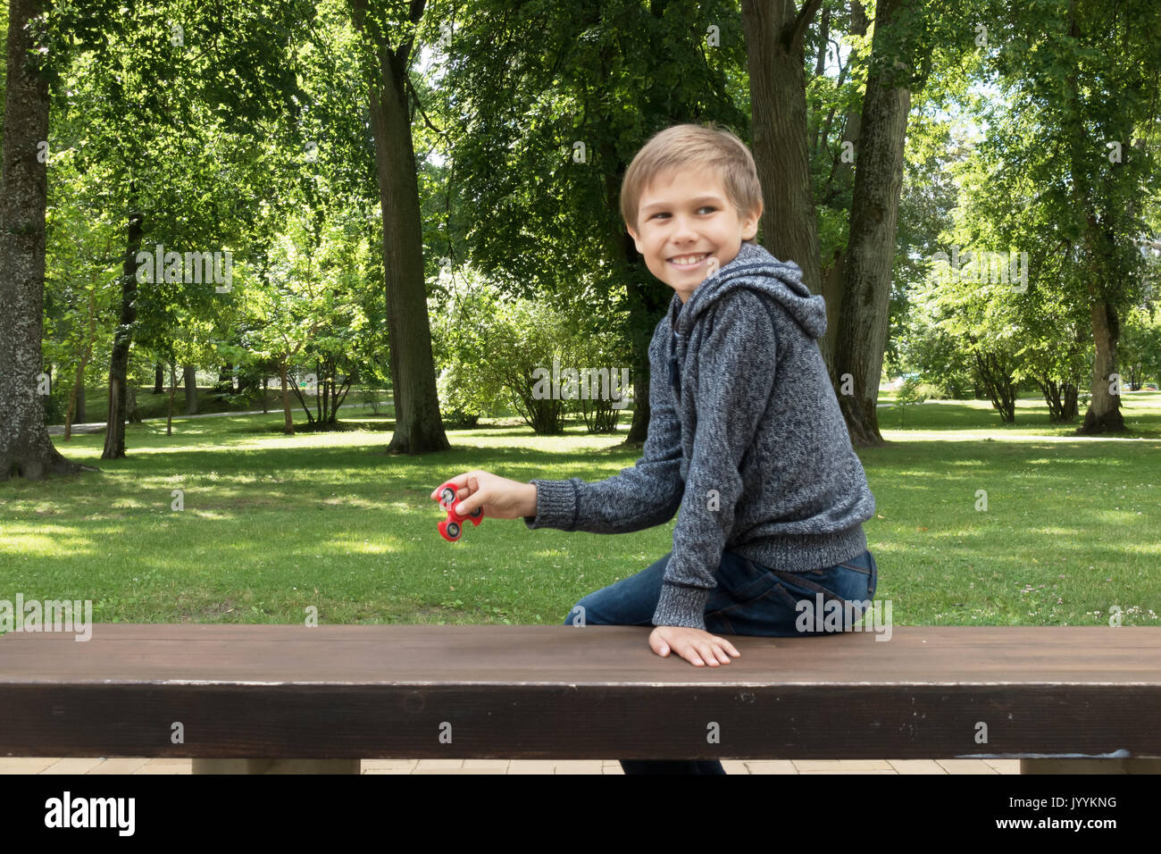 Kind sitzen auf dem Gras und spielt mit Spinner Stockfoto