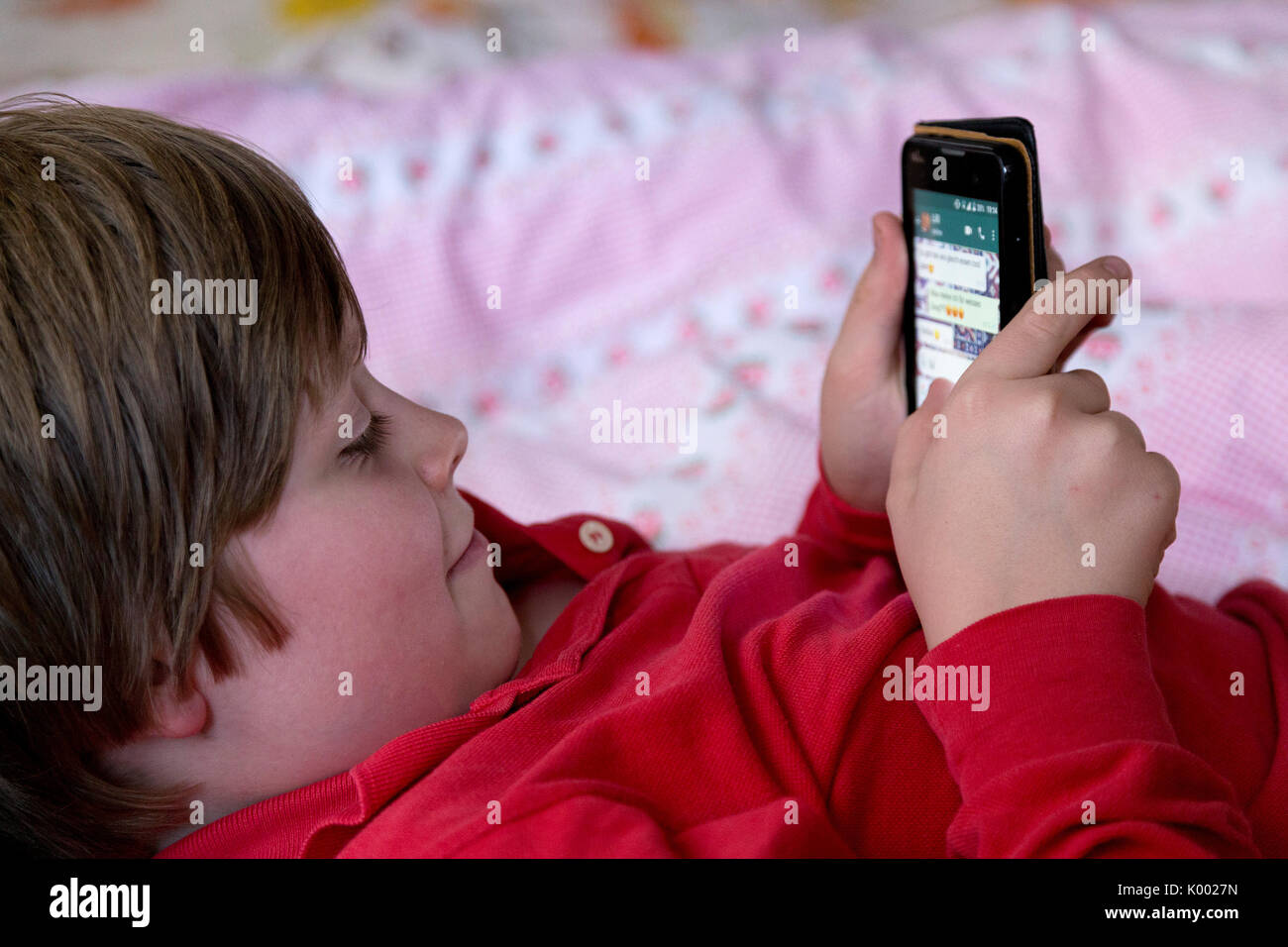 Junge lag auf seinem Bett mit seinem Smartphone Stockfoto