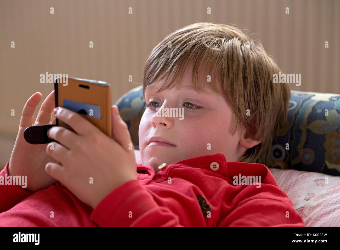 Junge lag auf seinem Bett mit seinem Smartphone Stockfoto