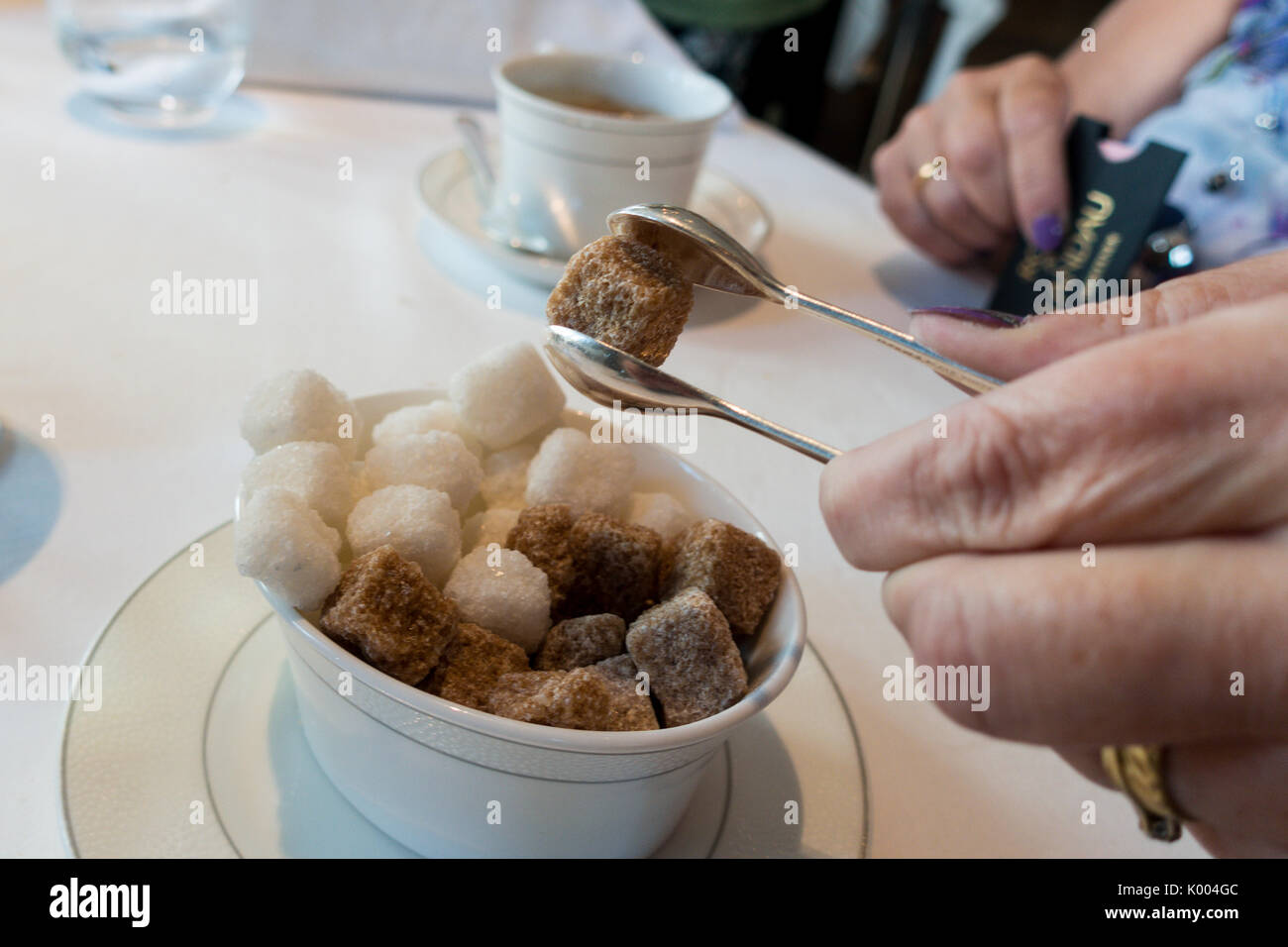 Frau unter raw Brown Sugar Cubes mit silbernen Zange an Roux an der Landau das Langham Hotel, 1 C Portland Pl, Marylebone, London W1B 1JA, Großbritannien Stockfoto