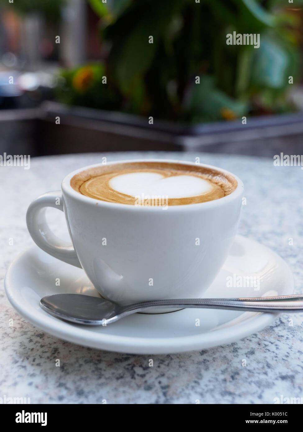 Herzförmige Kunst auf einen Cappuccino in einer Schale mit einem Löffel (außerhalb eines Cafe) Stockfoto