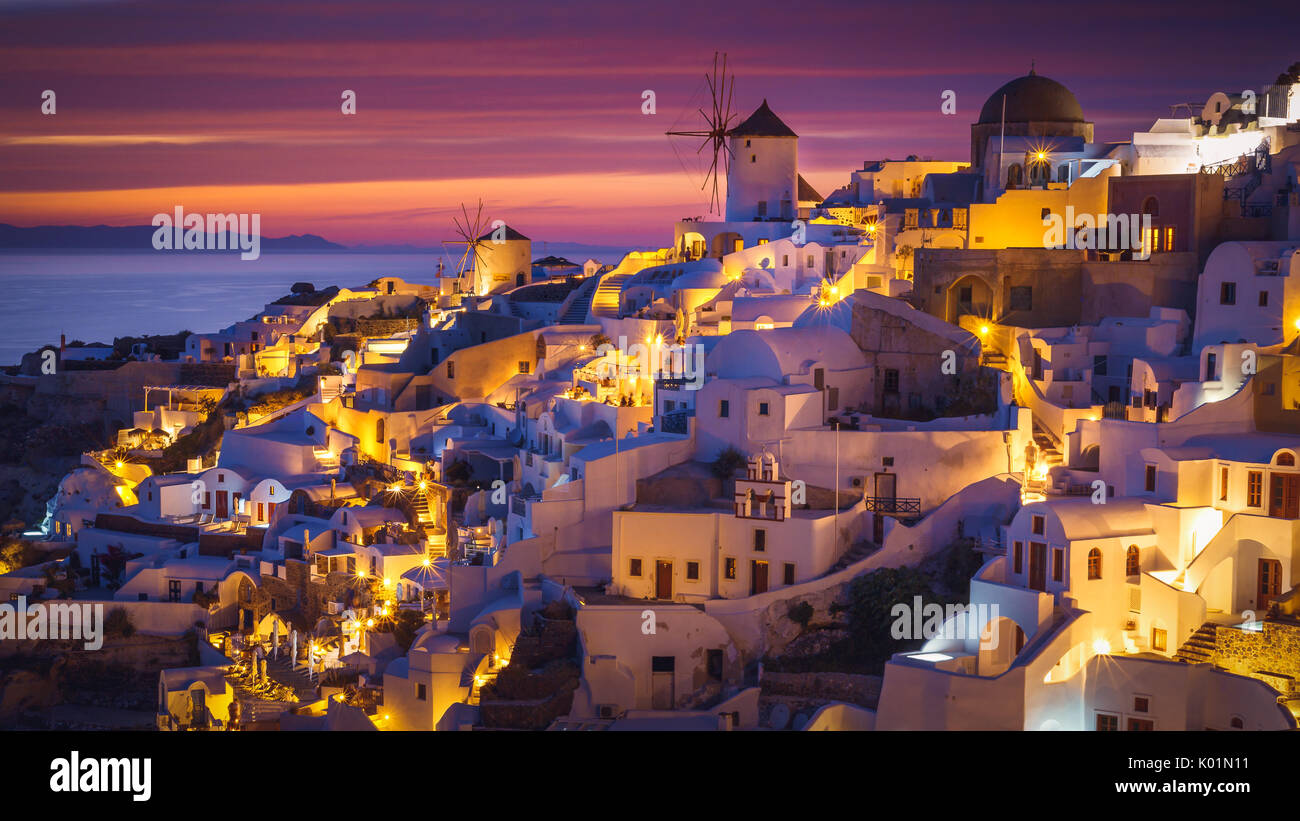 Farbenfroher Sonnenuntergang mit den Lichtern der Stadt in Oia, Santorini, Griechenland Stockfoto Farbenfroher Sonnenuntergang mit den Lichtern der Stadt in Oia, Santorini, Griechenland Stockfoto