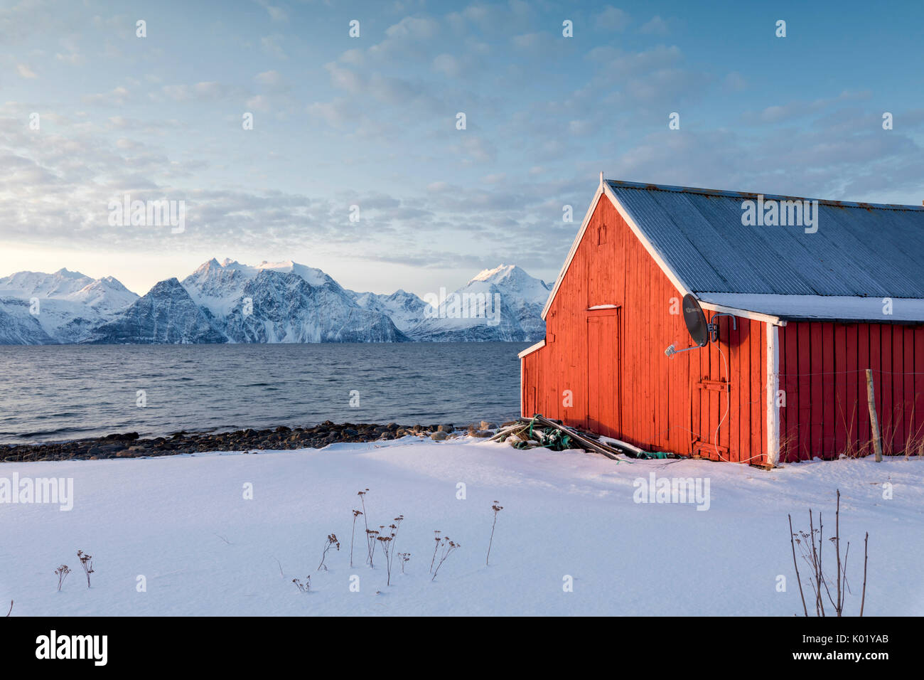 Blauer Himmel über die Holzhütten genannt Rorbu eingerahmt von gefrorenen Meer und schneebedeckten Gipfeln Djupvik Lyngen Alpen Tromsø Norwegen Europa Stockfoto