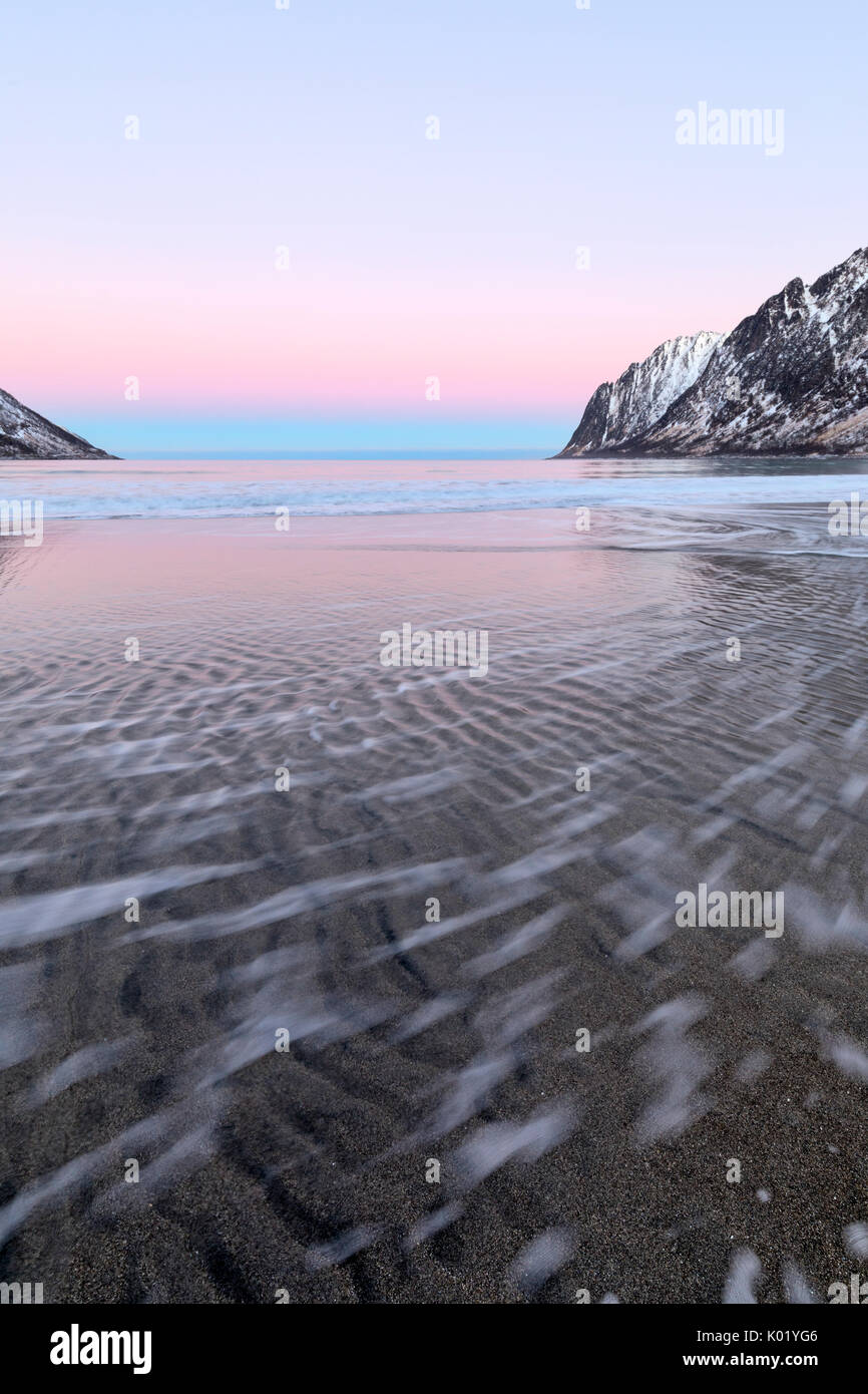 Die rosa Licht des Sonnenaufgangs Frames die Wellen der gefrorene Meer von schneebedeckten Gipfeln Ersfjord Senja Tromsø Norwegen Europa umgeben Stockfoto