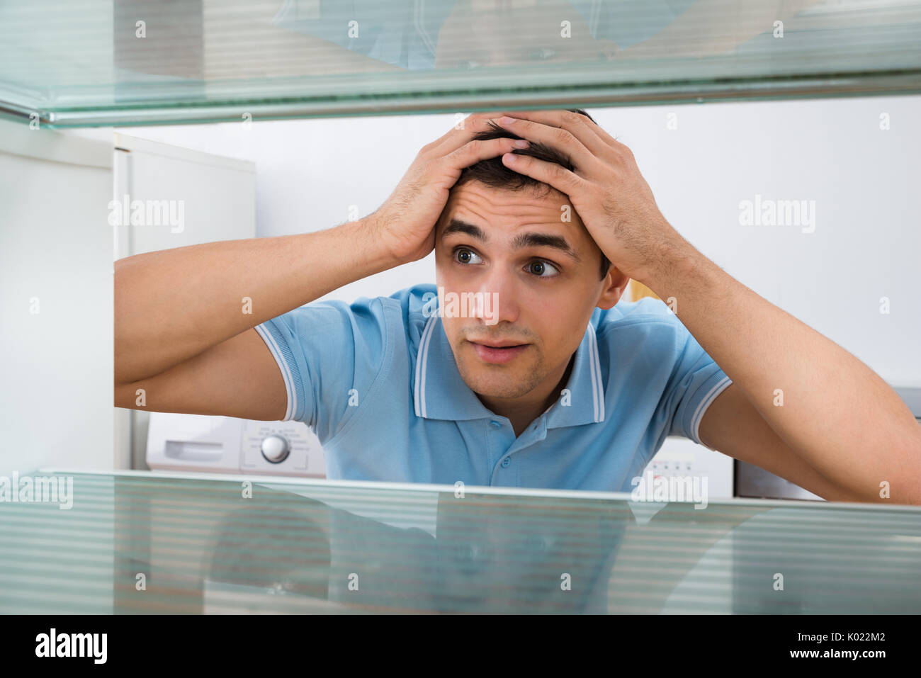 Junge Mann in leeren Kühlschrank zu Hause Schauen, Staunen Stockfoto