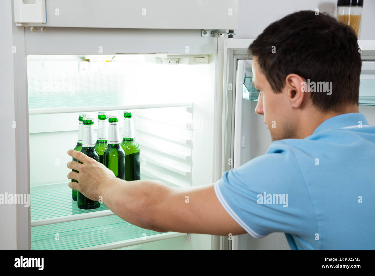 Seitenansicht des jungen Mannes entfernen Bier Flasche aus dem Kühlschrank zu Hause Stockfoto