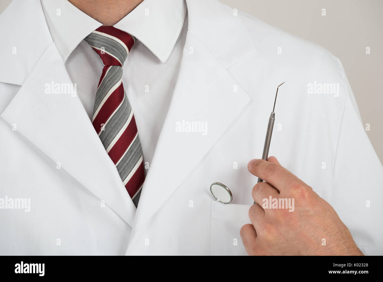 Mittelteil der Zahnarzt mit Werkzeugen in der Tasche vor weißem Hintergrund Stockfoto