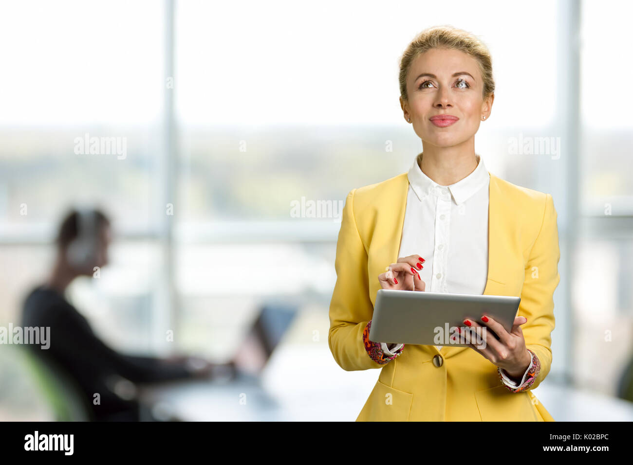 Nachdenklich business lady mit digitalen Tablet. Attraktive Frau mit einem digitalen Tablet beim Stehen vor der Fenster in einem Büro buildin Stockfoto