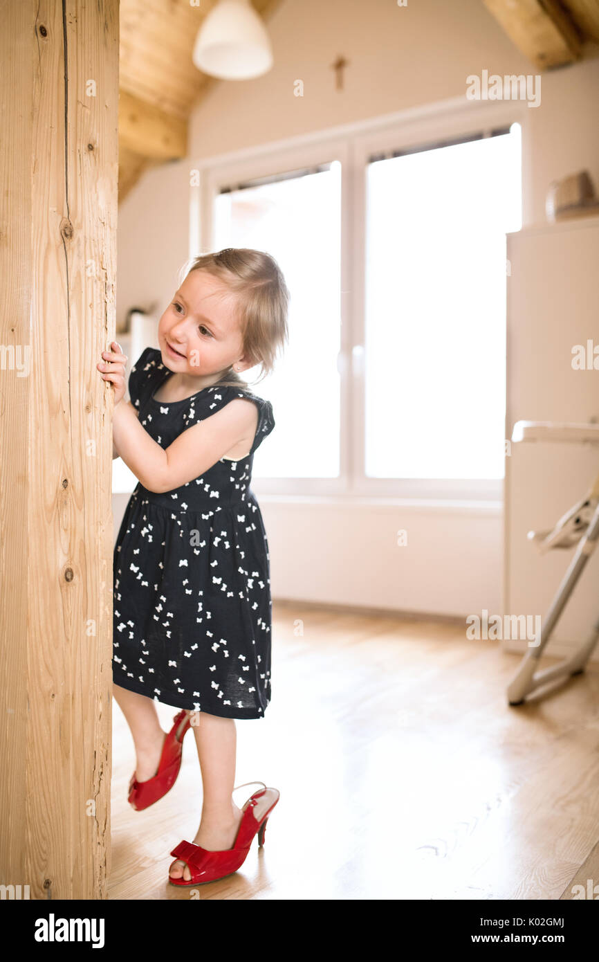 Süße kleine Mädchen im Kleid und roten High Heels zu Hause. Stockfoto