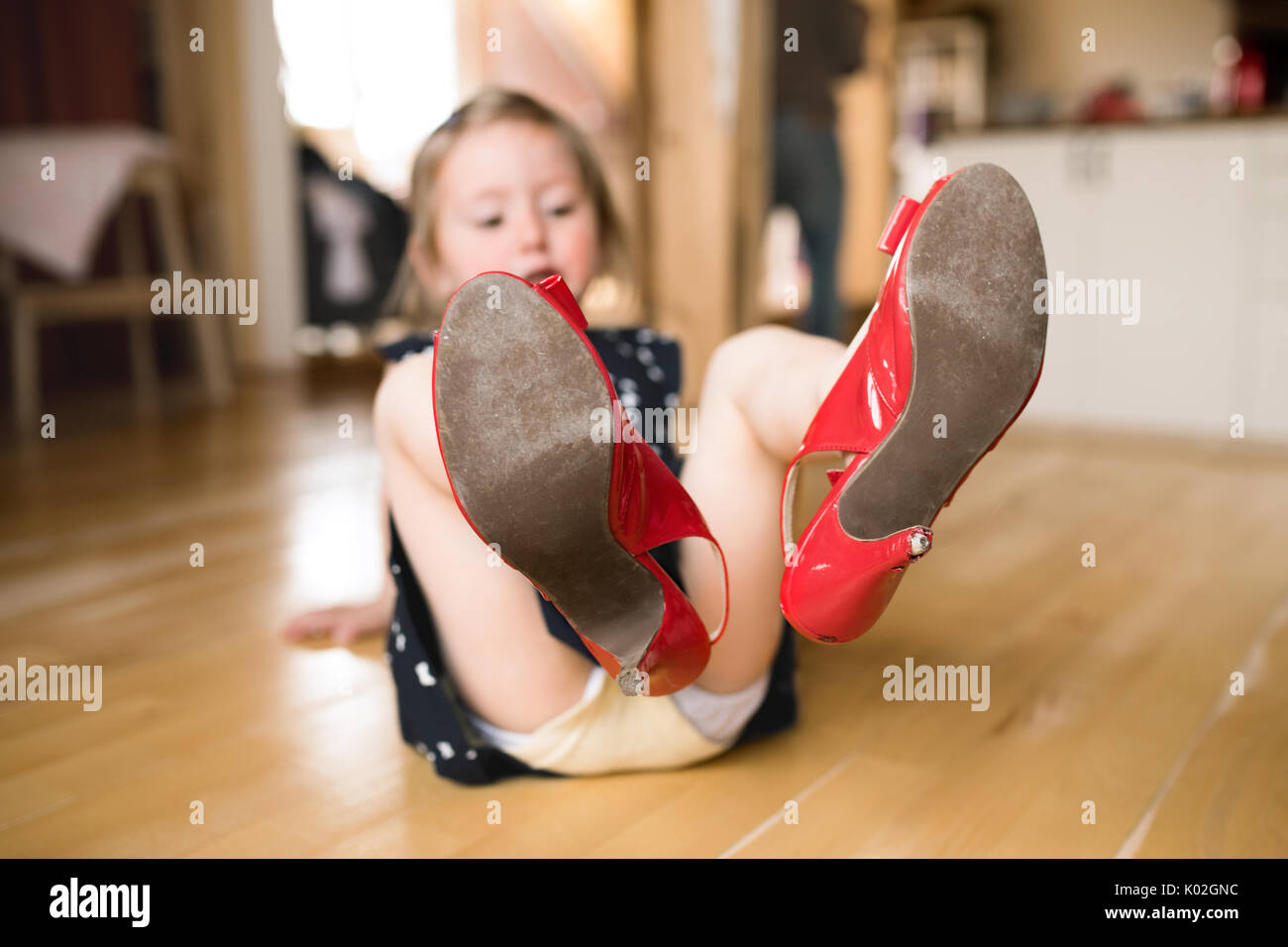 Kleines Mädchen im Kleid und roten High Heels zu Hause. Stockfoto