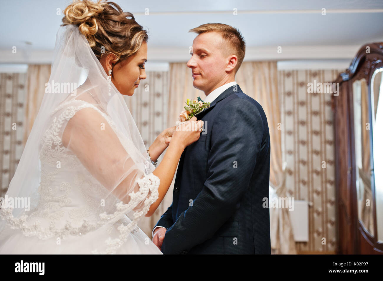 Attraktive Braut pinning Knopfloch Blume zu Jacke der Bräutigam am Hochzeitstag. Stockfoto