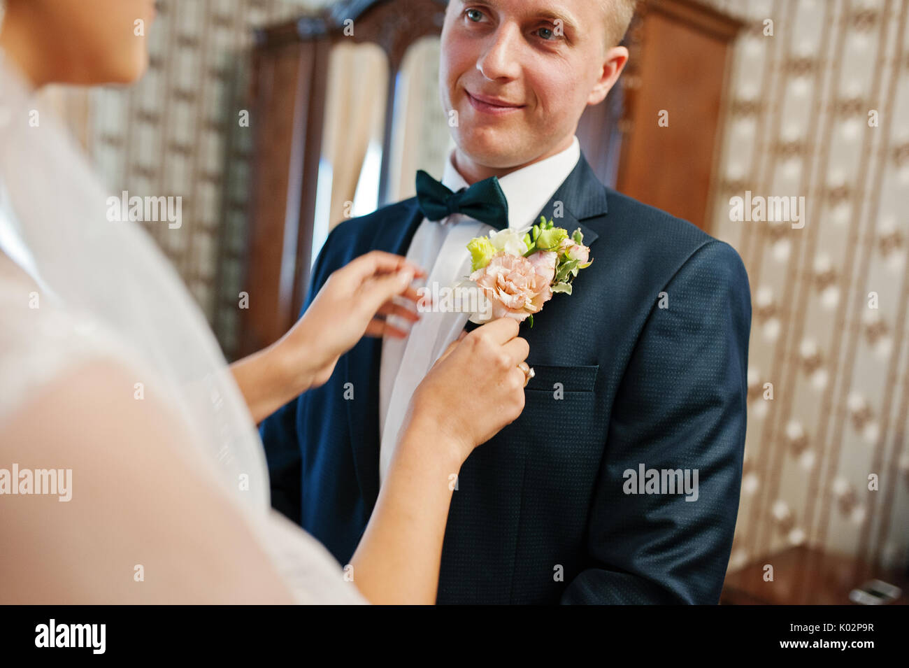 Attraktive Braut pinning Knopfloch Blume zu Jacke der Bräutigam am Hochzeitstag. Stockfoto