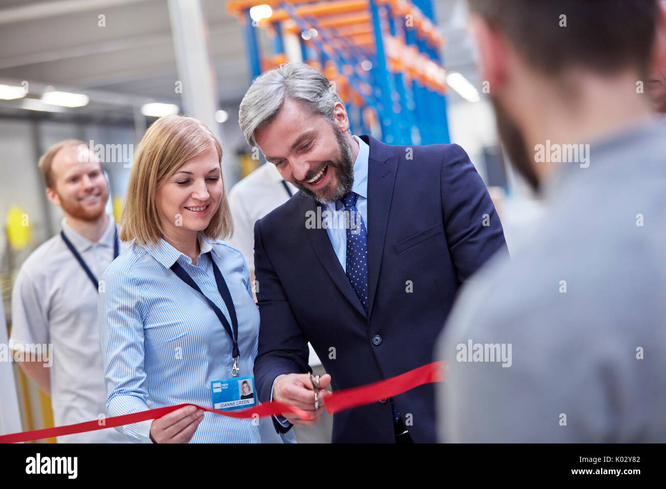 Kaufmann und Kauffrau schneiden zeremoniellen Ribbon in Fiber Optik Factory Stockfoto