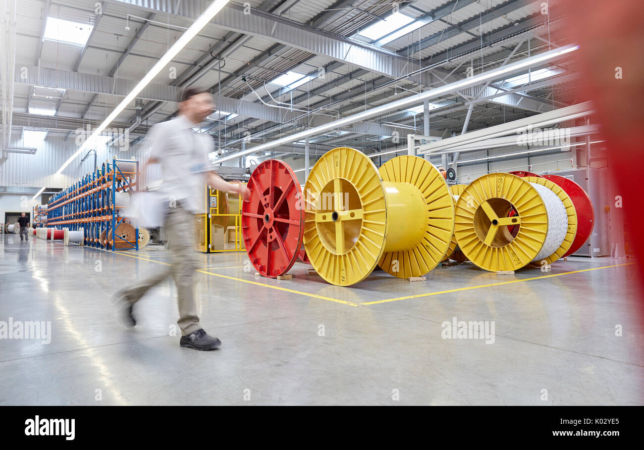 Männlichen Arbeitnehmer zu Fuß durch große Spulen in Fiber Optik Factory Stockfoto