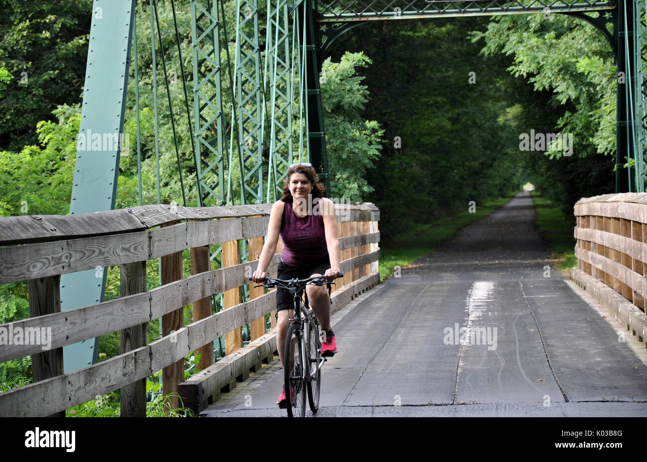 Frau Radfahren über eine Brücke auf der Western Reserve Greenway Trail in Ashtabula County, Ohio Stockfoto