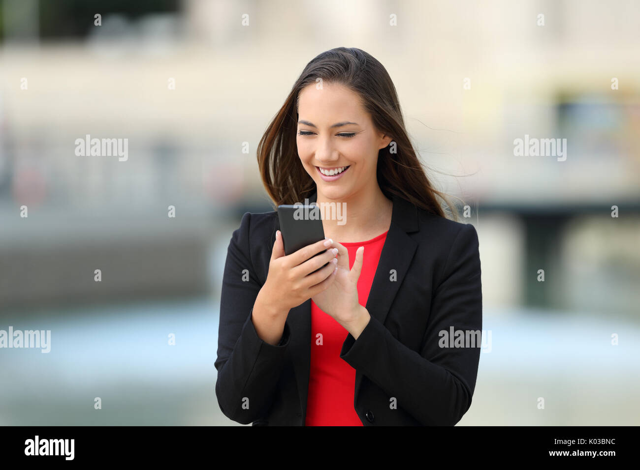 Happy Executive zu Fuß und mit Phone draußen auf der Straße Stockfoto