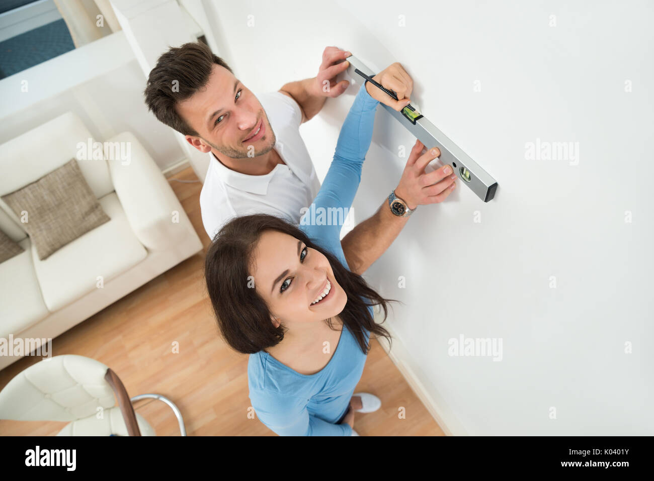 Glückliches Paar Kennzeichnung mit Bleistift auf der Wand mit Niveau im Haus Stockfoto