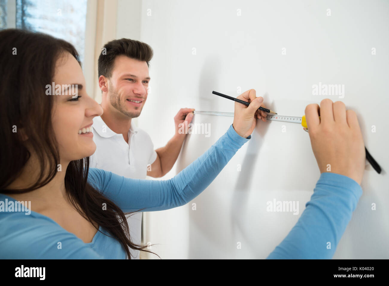 Nahaufnahme des jungen Paares Messen Wand mit Messung Klebeband und Bleistift Stockfoto