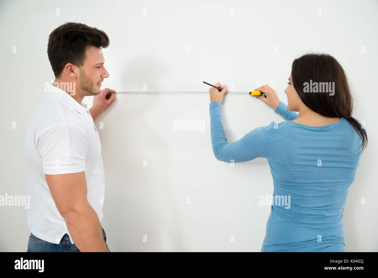 Nahaufnahme des jungen Paares Messen Wand mit Messung Klebeband und Bleistift Stockfoto