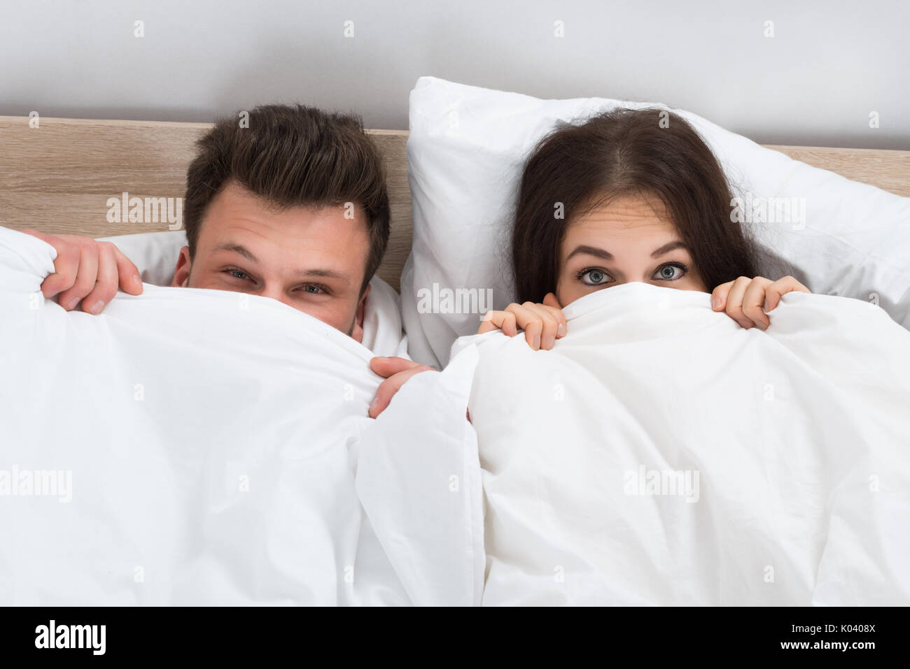 Porträt eines jungen Paares ausblenden Gesicht mit Decke im Schlafzimmer Stockfoto