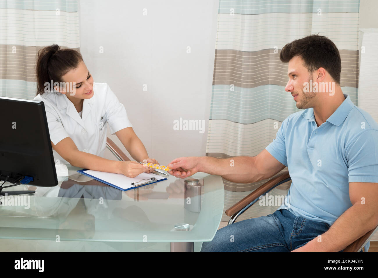 Junge weibliche Arzt, der Pillen zu Männlichen Patienten in der Klinik Stockfoto