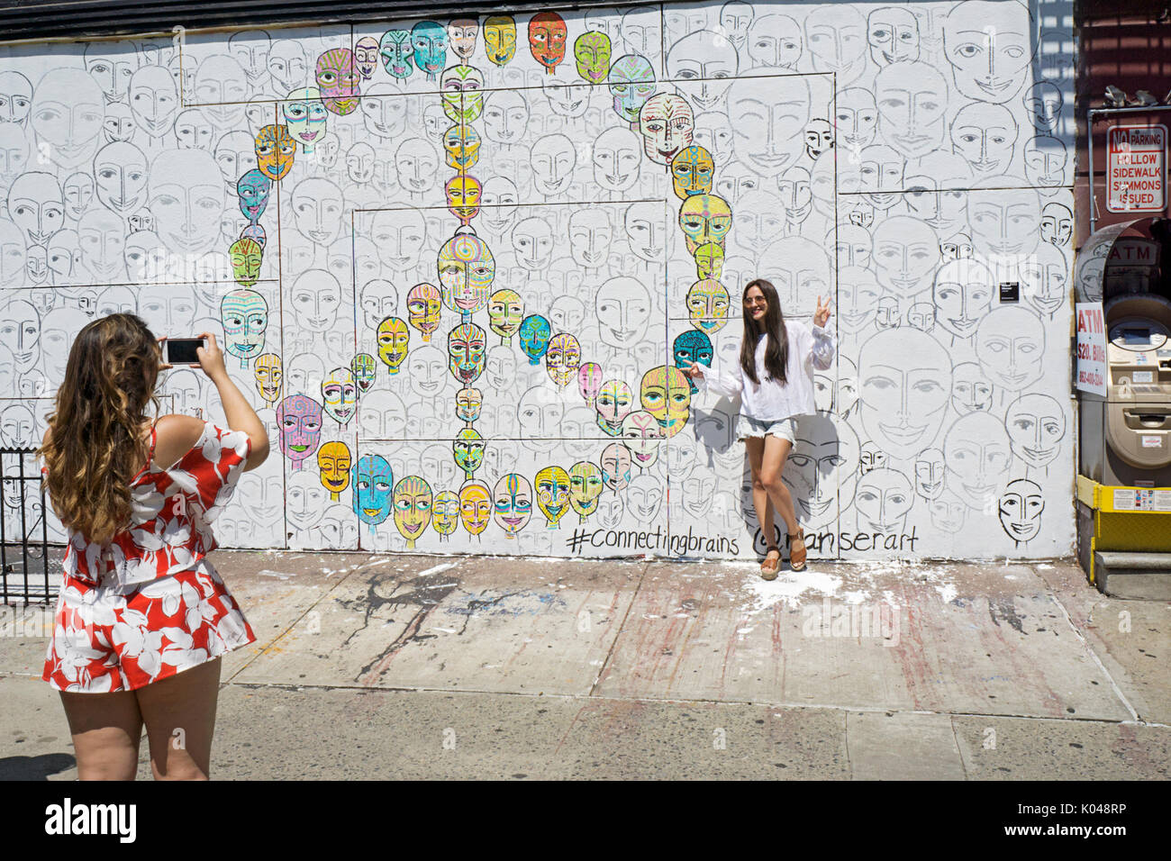 Zwei Frauen, vermutlich Touristen, Fotos machen vor einer Graffiti-wand der Kenmare Street Ecke von Mott in der nolita Teil von Downtown NEW YORK CITY. Stockfoto