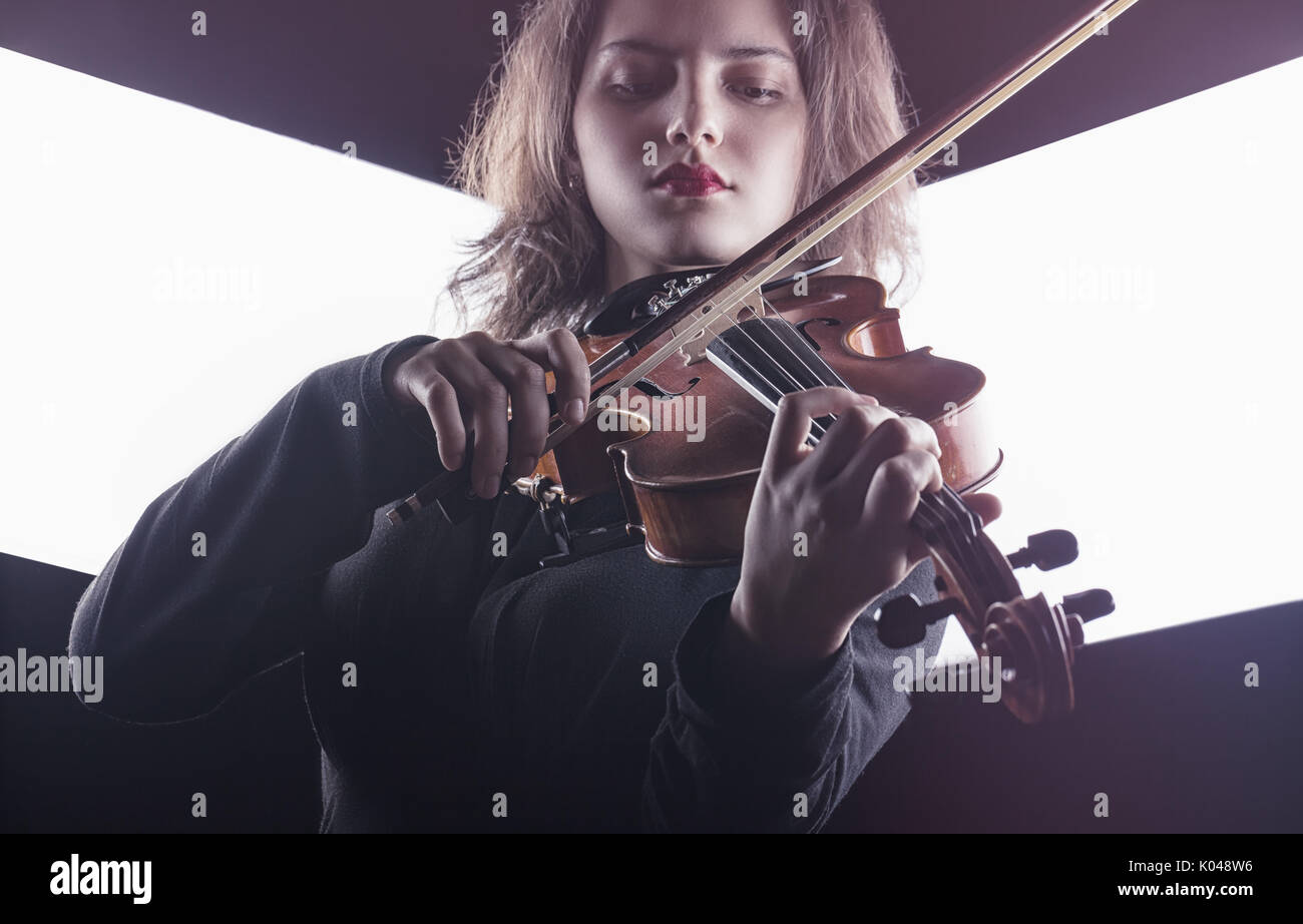 Schöne junge Frau spielt die Geige auf dunklem Hintergrund Stockfoto