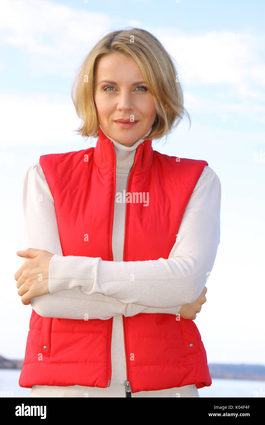 Hübsche blonde Frau mittleren Alters in einem Herbst Spaziergang an einem See. Stockfoto