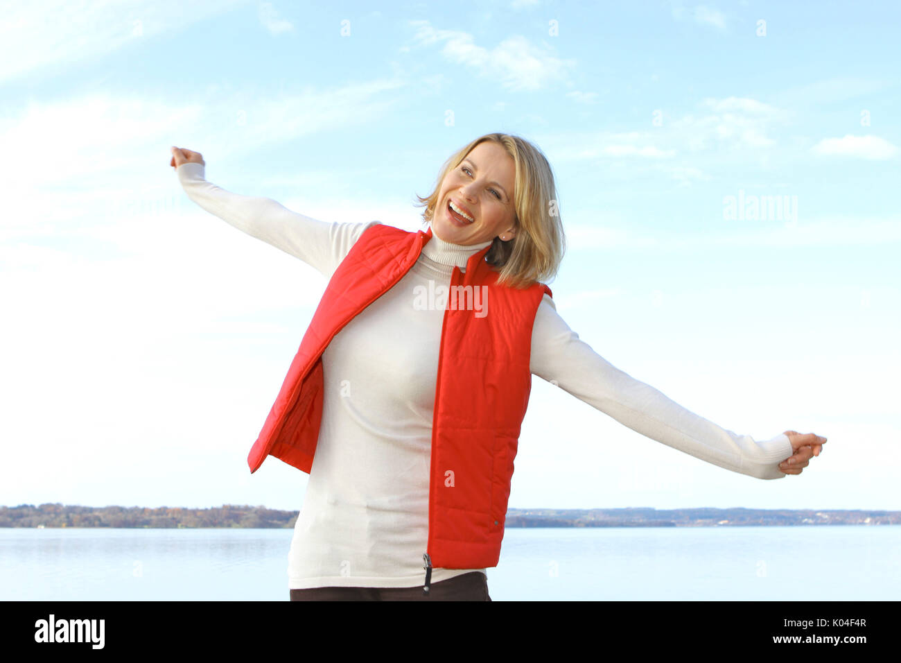 Hübsche blonde Frau mittleren Alters in einem Herbst Spaziergang an einem See. Stockfoto