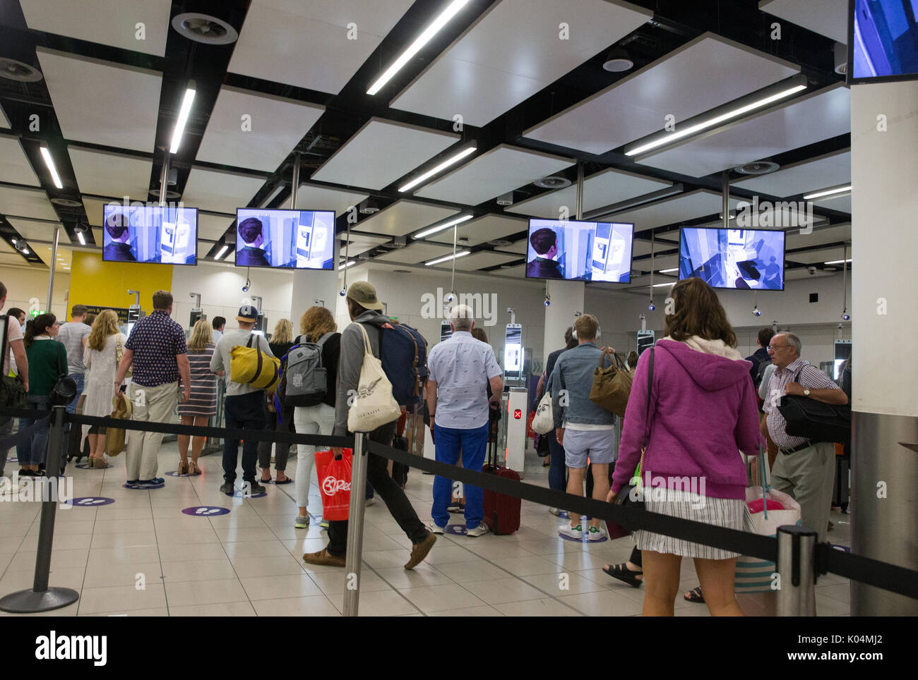 Die Menschen an der britischen Grenze auf dem Flughafen Gatwick wartete durch den Epass Tore zu gehen Pass details zu überprüfen. Das System verwendet die Iriserkennung. Stockfoto