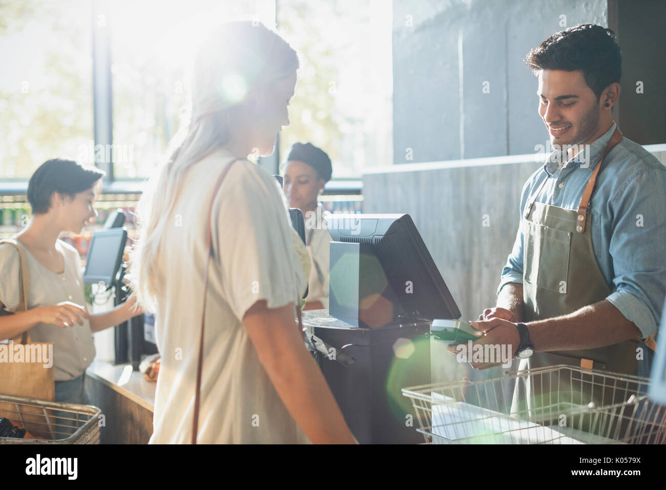 Männliche Kassierer helfen weiblichen Shopper an der Supermarkt Kasse Stockfoto