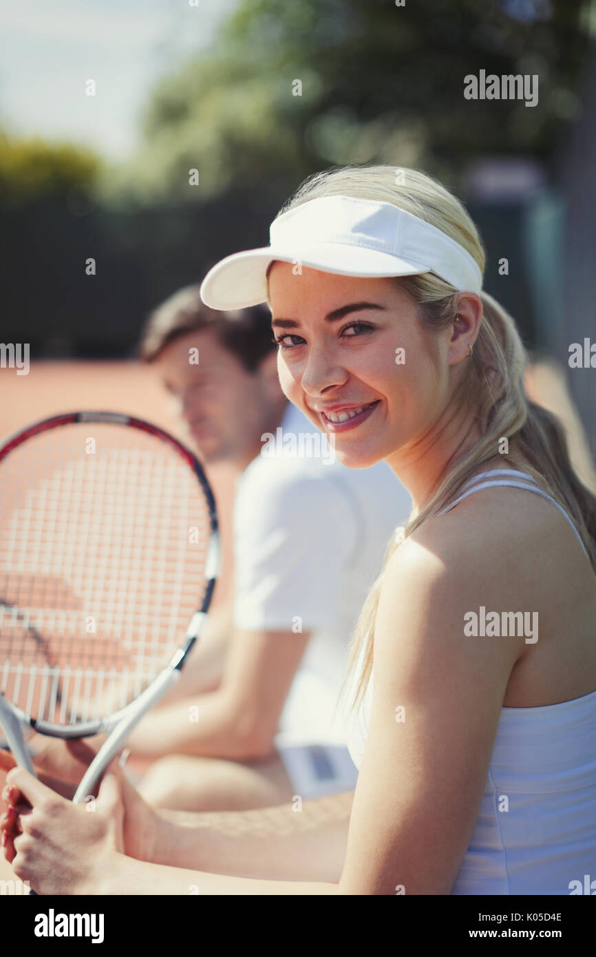 Porträt Lächeln, selbstbewussten jungen Frau tennis Spieler mit Tennisschläger an sonnigen Tennisplatz Stockfoto