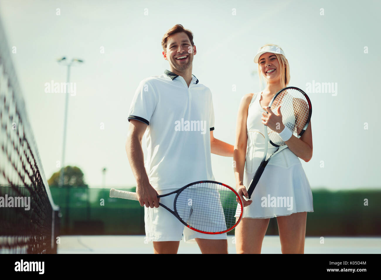 Porträt Lächeln, zuversichtlich Tennisspieler holding Tennisschläger an sonnigen Tennisplatz Stockfoto