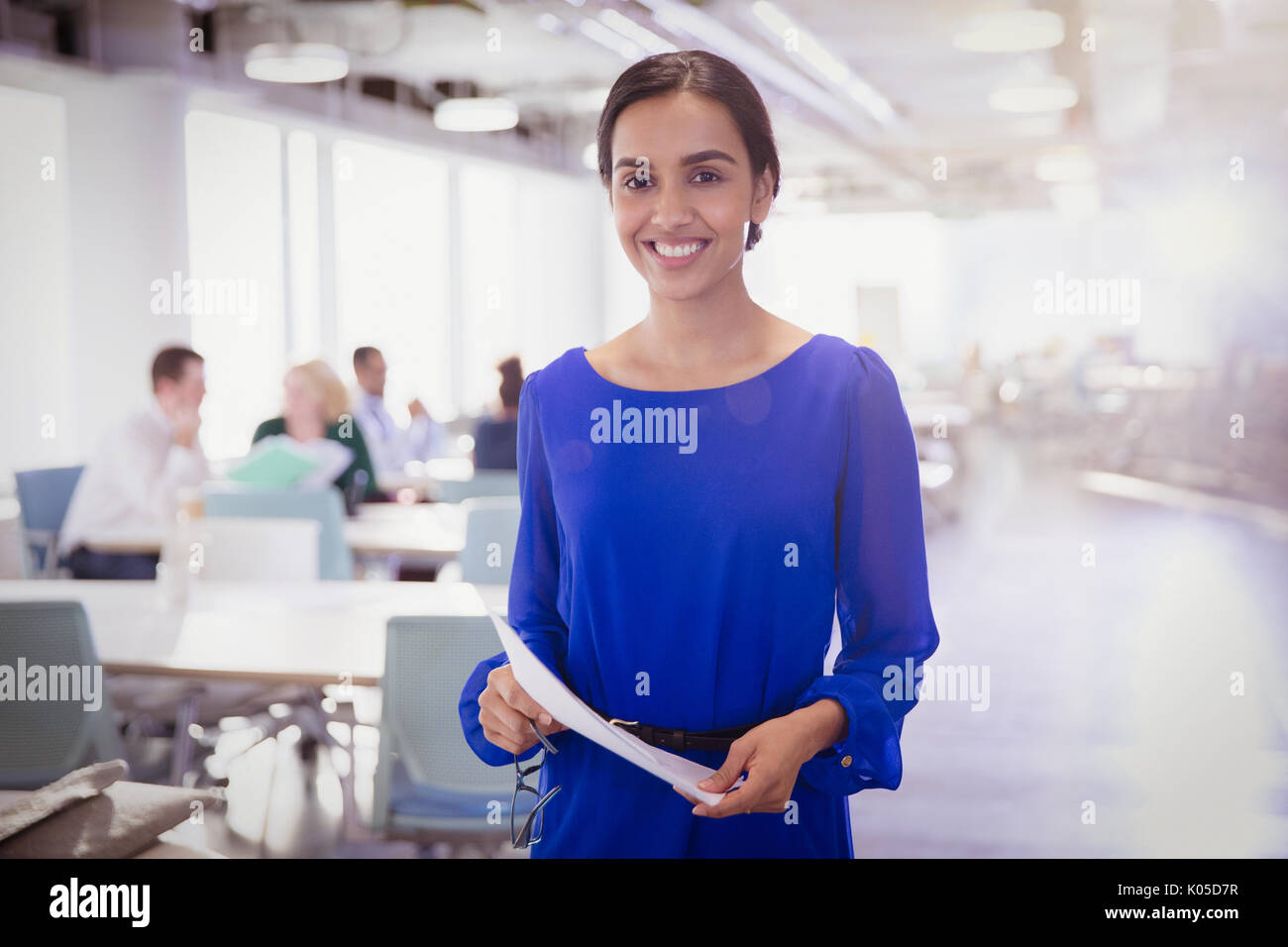 Porträt lächelnd Geschäftsfrau mit Papierkram im Büro Stockfoto