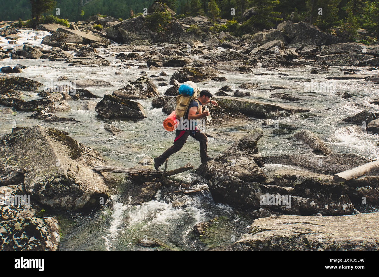 Junge Wanderer Kreuzung mountain river. Fany Berg. Wandern River Crossing auf den Steinen. Tadschikistan Stockfoto