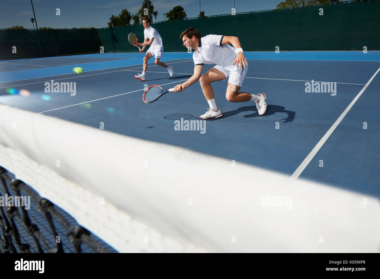 Junge männliche Tennis Doubles Spieler Tennis spielen auf Tennisplatz Stockfoto