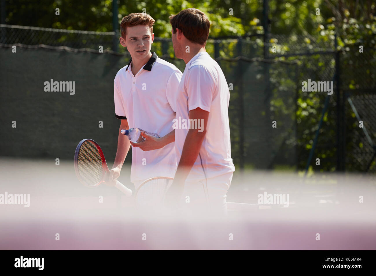 Männliche tennis Spieler mit Tennisschläger sprechen an sonnigen Tennisplatz Stockfoto