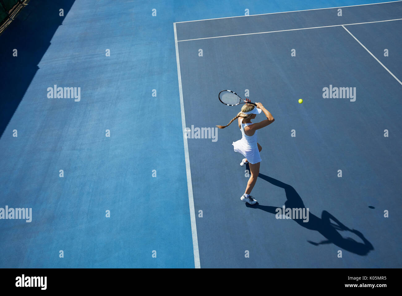 Ansicht von oben Junge weibliche Tennisspieler Tennis spielen auf sonnigen blauen Tennisplatz Stockfoto