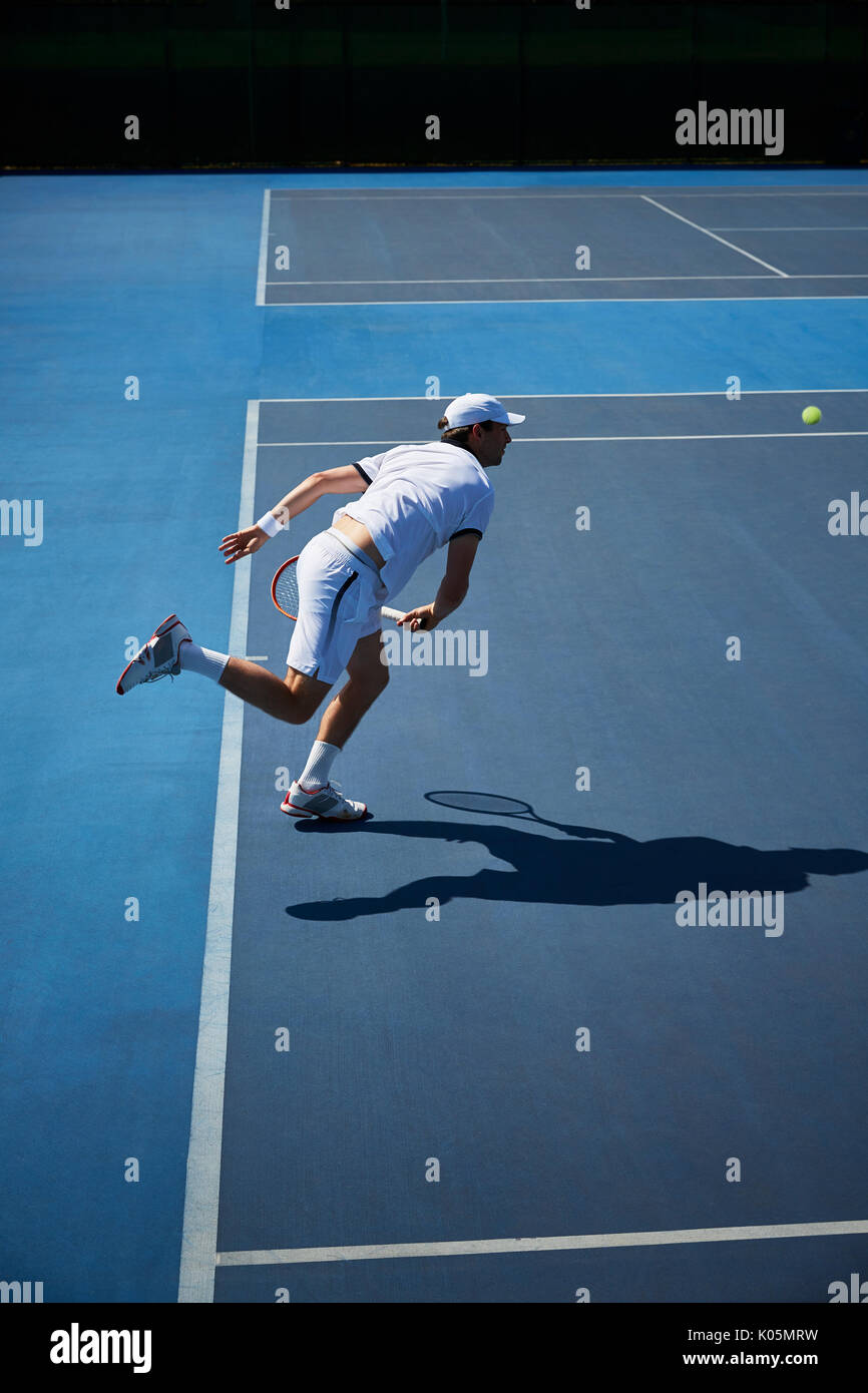 Männliche tennis player Tennis spielen auf sonnigen blauen Tennisplatz Stockfoto