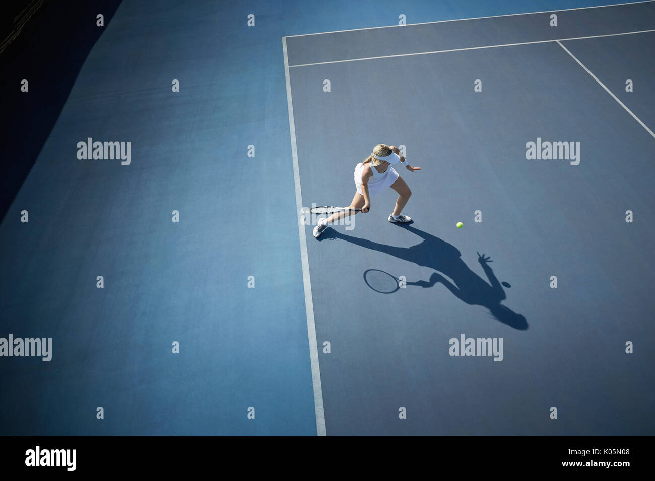Ansicht von oben Junge weibliche Tennisspieler Tennis spielen, den Ball schlagen auf sonnigen blauen Tennisplatz Stockfoto